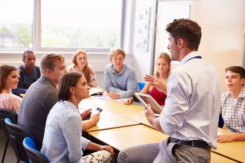 Teacher With College Students Giving Lesson In Classroom